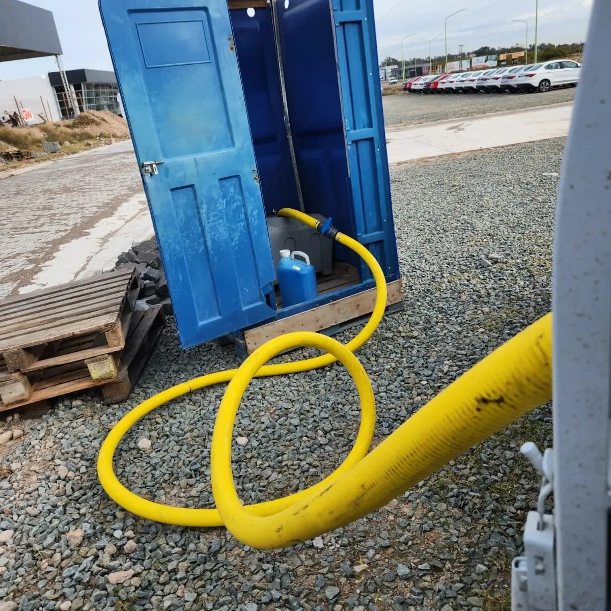 Limpieza de un baño químico en obra con manguera de succión y producto desinfectante