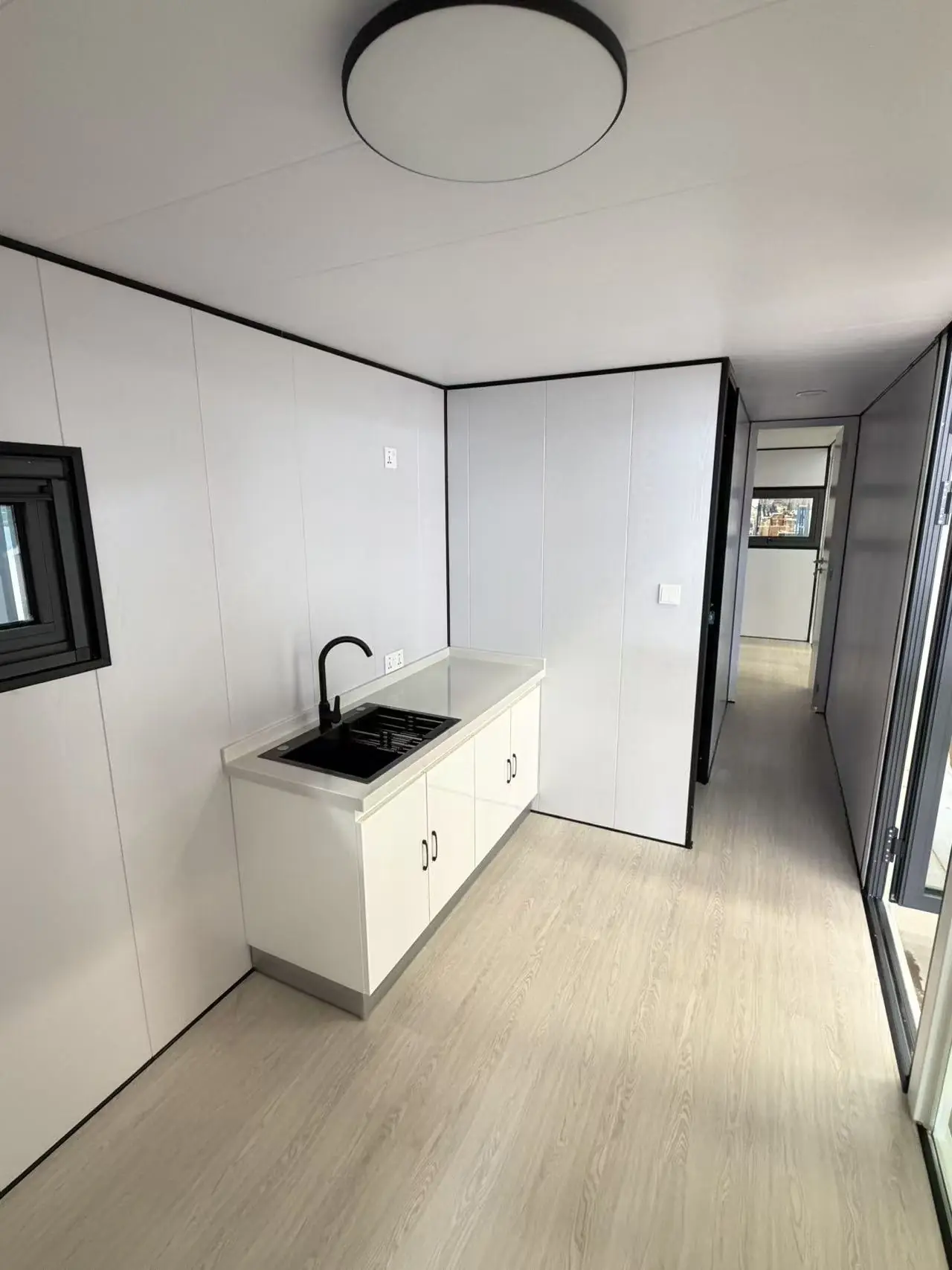 Cocina de una Apple Cabin con bacha negra, mesada clara y bajo mesada blanco, junto al pasillo a los otros ambientes