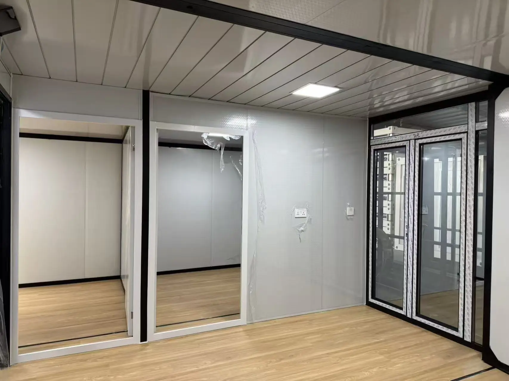 Interior de una casa expandible con las entradas a dos dormitorios y la puerta doble vidriada, todavía con film protector