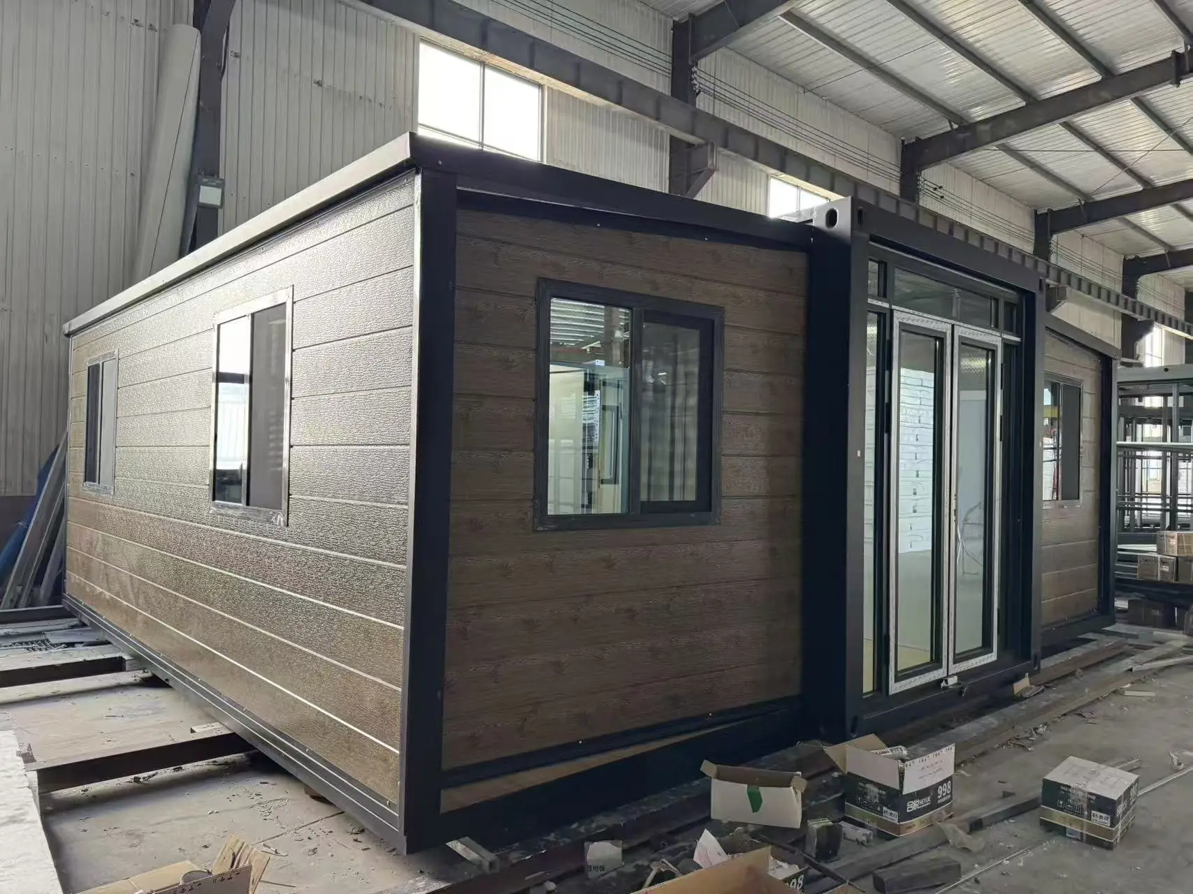 Casa expandible desplegada vista de costado, con ventanas corredizas y la puerta doble vidriada al centro