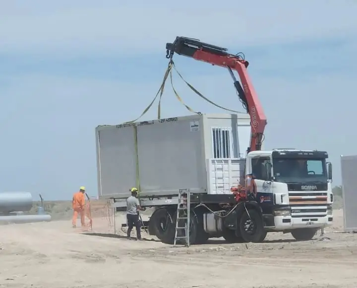 Hidrogrúa sobre camión Scania instala un módulo en una obra, con operarios con casco