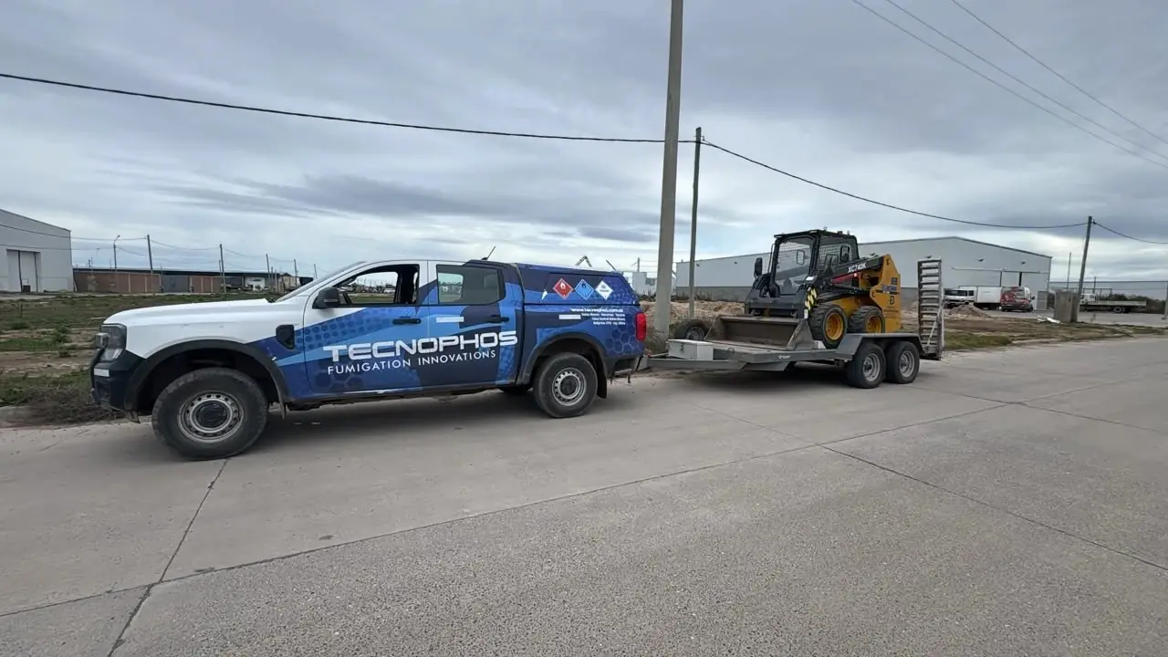 Minicargadora XCMG sobre un tráiler remolcado por una camioneta, lista para la entrega
