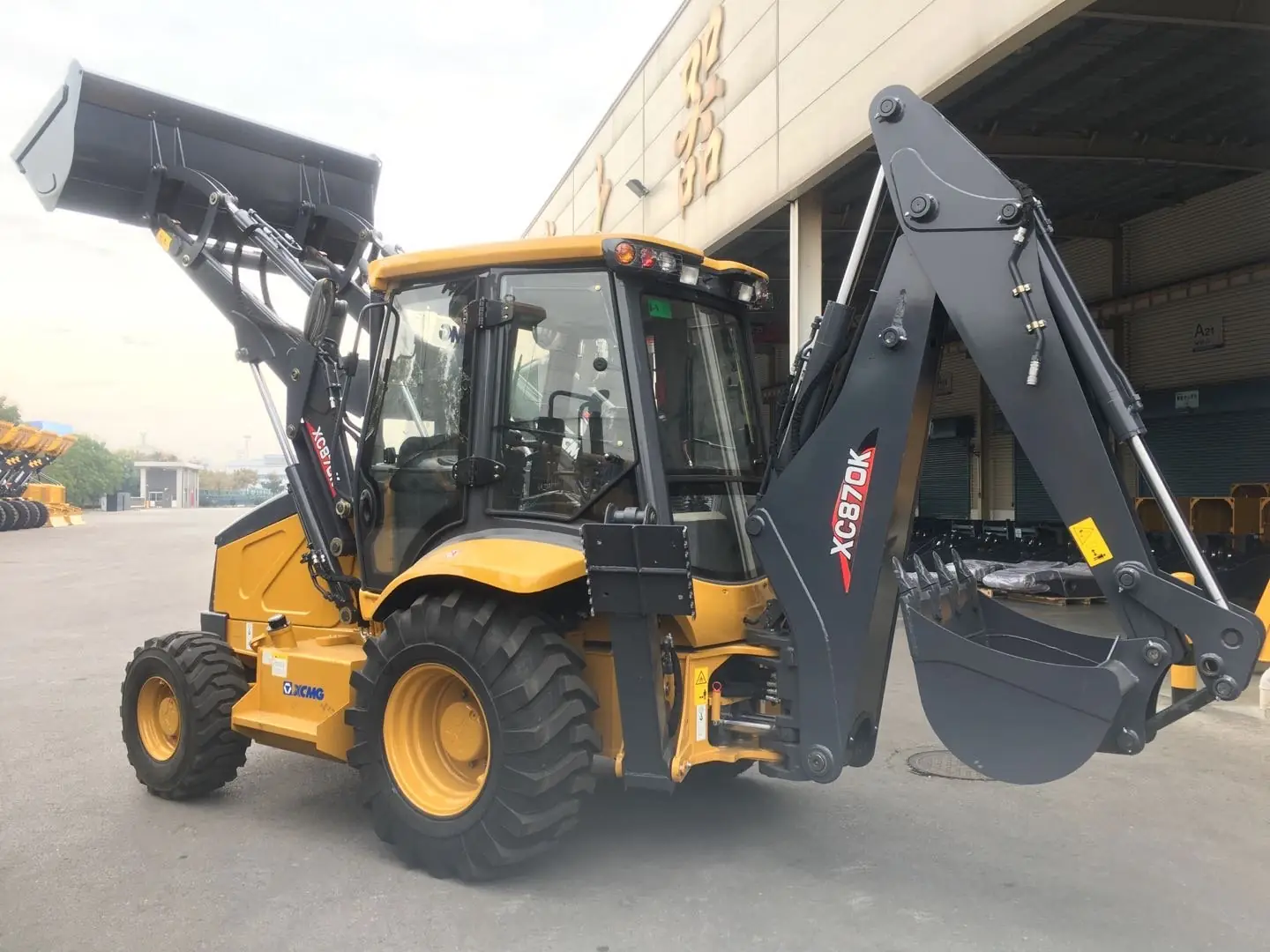 Retroexcavadora XCMG XC870K amarilla con pala frontal levantada y brazo retro extendido