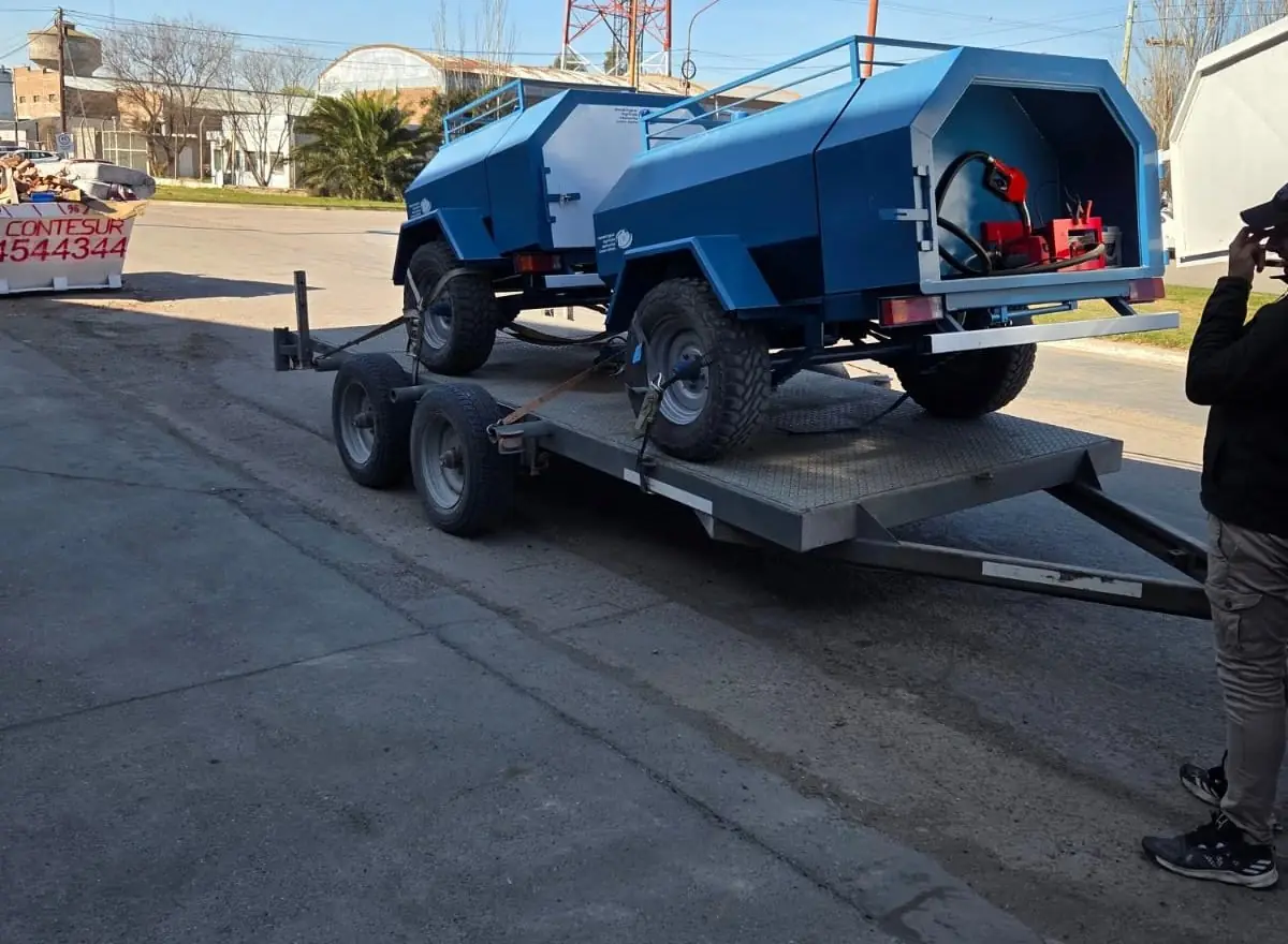 Dos tanques de combustible azules sobre tráiler, con bomba y pico surtidor, cargados en una plataforma