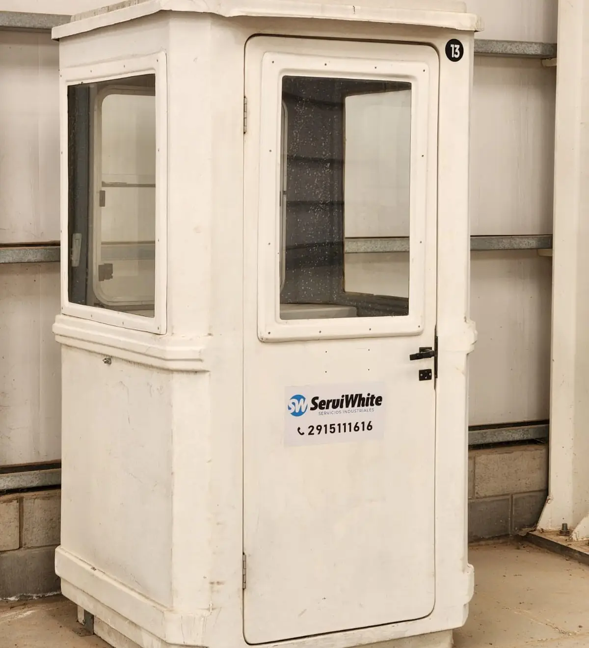 Garita de seguridad blanca de fibra de vidrio con ventanas y el logo de Serviwhite en la puerta