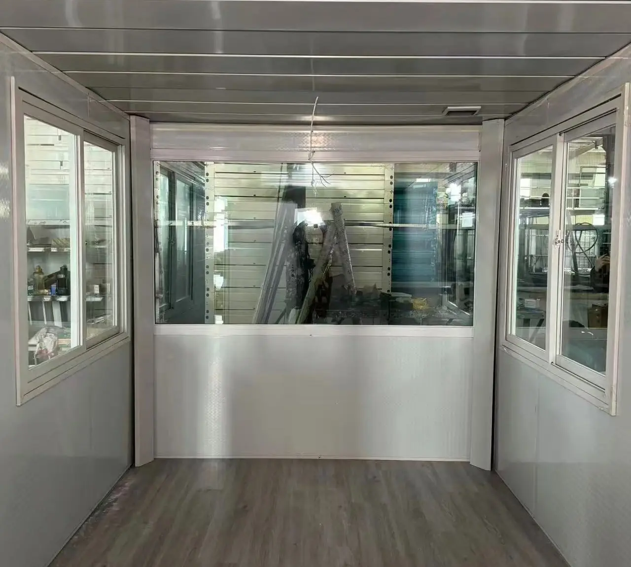 Interior de un módulo de control con ventanal al frente, ventanas laterales y piso vinílico