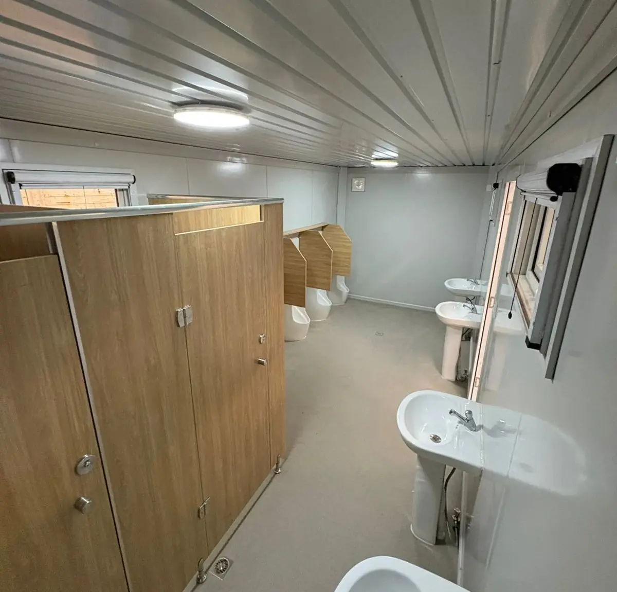 Módulo sanitario con boxes, mingitorio y dos lavatorios, iluminado con plafón LED