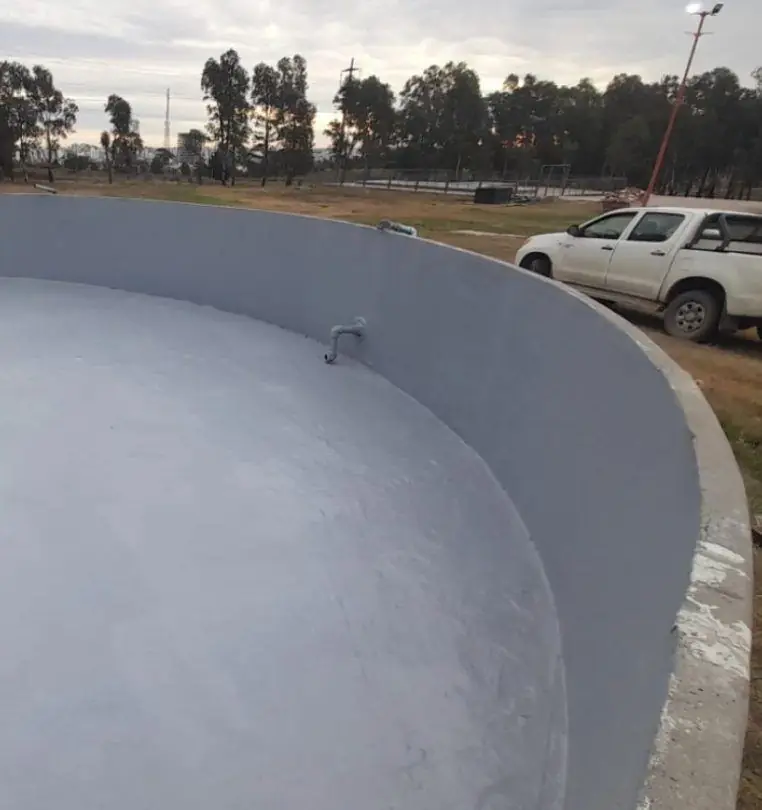Cisterna circular de hormigón con revestimiento interior gris terminado, junto a una camioneta blanca