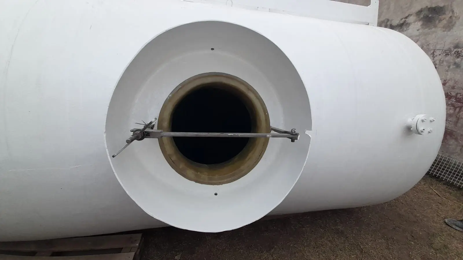 Tanque horizontal de PRFV blanco con boca de hombre abierta y una conexión bridada